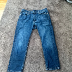 Levis 541 blå jeans - Klassiska blå Levis 541 jeans med raka ben och femficksmodell. Jeansen har normal passform och är tillverkade i slitstarkt denim. Perfekta för dig som gillar tidlös stil och vill ha ett par jeans som funkar till det mesta. Storlek 36/30.