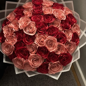 Bukett med konstgjorda rosor i rött och rosa - En stor och lyxig bukett med konstgjorda rosor i olika nyanser av rött och rosa. Rosorna är tätt packade och omslutna av transparent inslagningspapper, perfekt som dekor eller present.