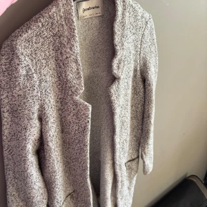 Gråmelerad cardigan jacka från Stradivarius - Säljer en gråmelerad cardigan jacka från Stradivarius i storlek S. Jackan har lång ärm, öppen front och två fickor med dragkedja. Perfekt för lager-på-lager och enkel att matcha med olika outfits.