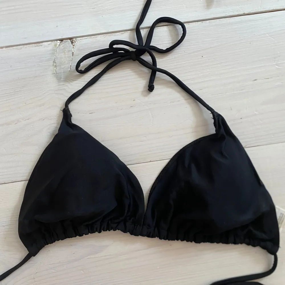 Snygg svart bikiniöverdel med knytband i nacken och ryggen. Perfekt för en dag på stranden eller vid poolen. Enkel och stilren design som passar till det mesta.. Muu.