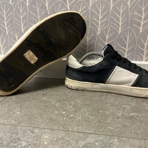 Valentino flycrews  - Snygga Valentino flycrews i en kombination av mörkblå mocka och vit skinn. Skorna har mörkblåa snören och en vit sula med subtila detaljer. Perfekta för en stilren look. Storlek 43. Dust bag ingår. Tar gärna emot byten!! Hör av er vid frågor eller funderingar!