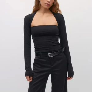 Svart axelbandslös topp med bolerotopp - Snygg svart axelbandslös topp med en matchande bolerotopp. Perfekt för en stilren look. Toppen är tight och har långa ärmar på bolerotoppen.