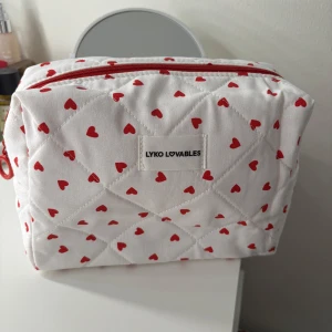 Vit necessär med röda hjärtan från Lyko Lovables - Söt vit necessär med quiltat mönster och röda hjärtan från Lyko Lovables. Den har en praktisk dragkedja upptill och är perfekt för att förvara smink eller andra småsaker. Perfekt att ha med på resan eller i handväskan.
