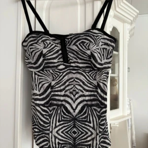 Zebramönstrad bad/topp från Trofé - Snygg zebramönstrad baddräkt eller topp från Trofé med svarta axelband och en elegant design. Perfekt för en dag på stranden eller vid poolen. Baddräktsmaterial