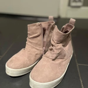 Rosa boots med dragkedja - Snygga rosa boots i mocka med dragkedja på sidan och vit sula. Perfekta för en stilren look med en touch av färg. Skostorlek 35. Dessa är från Din Sko ✨