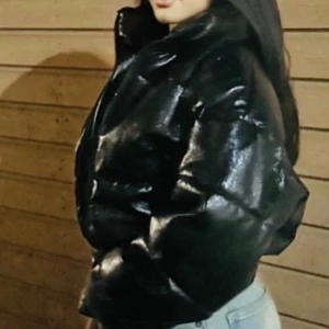 Svart glansig pufferjacka - Snygg svart pufferjacka med glansig yta. Jackan har en dragkedja framtill och långa ärmar. Perfekt för att hålla värmen med stil.