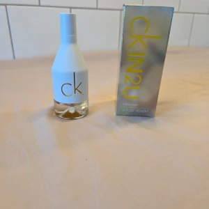 CK IN2U Parfym - Säljer en stilren CK IN2U parfym från Calvin Klein. Flaskan har en modern design i vitt med genomskinlig botten och guldtext. Perfekt för den som gillar en fräsch och ungdomlig doft. Använd pyttelite