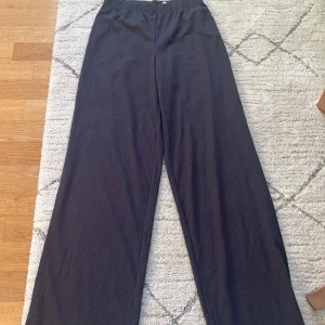 Svarta vida byxor - Snygga svarta byxor med en loose passform och hög midja. De har en diskret randig textur.