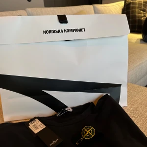 Svart tröja från Stone Island - Säljer en stilren mörkblå tröja från Stone Island med deras ikoniska märke på ärmen. Tröjan har långa ärmar och en klassisk rund halsringning. Perfekt för en avslappnad och trendig look.