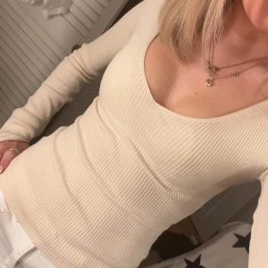 Beige ribbad tröja - Säljer en stilren beige ribbad tröja med v-ringning. Tröjan har långa ärmar och en tight passform oc splittrat slut på armarna 