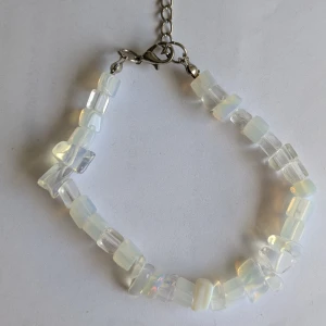 Armband med opaliserande pärlor - Snyggt armband med opaliserande pärlor som skiftar i färg. Pärlorna är fyrkantiga och sitter på en kedja med justerbar längd och karbinhake. Perfekt för att ge en magisk touch till din stil.
