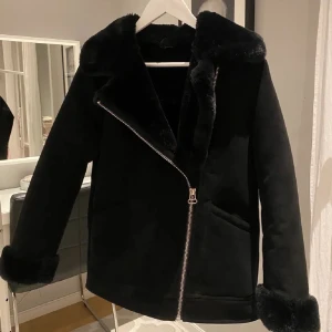 Svart jacka med pälsdetaljer - Perfekt jacka för kyligare dagar, jag har användt den några gånger men inga tecken på användning. Jätte mysig insida och utsida, fickor finns med. Köpt på H&M 