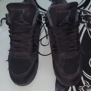 Black cats nike Jordans 4 - Snygga svarta Nike Air Jordans med klassisk design och snörning. Skorna har en stilren look med diskreta detaljer och är perfekta för både vardag och träning.