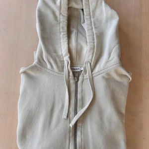 Beige hoodie från Filippa K - Säljer en skön beige hoodie från Filippa K. Med silvrig  dragkedja framtill och en  huva med dragsko, blir denna ett skönt och avslappnat, men samtidigt stilrent val. Perfekt för vardagen. 