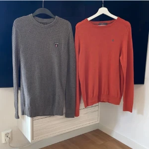 Grå och orange tröja från Morris - Två stiliga tröjor från Morris. Den gråa tröjan har ett diskret mönster och en liten broderad logga på bröstet, medan den orangea tröjan är i 100% merinoull och har en enkel design. Båda tröjorna har långa ärmar och ribbade muddar.Hör bara av dig om du bara vill köpa ena!