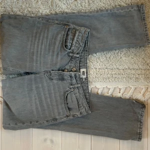Grå jeans från 157 - Snygga grå jeans från 157 med knappgylf. Perfekta för en avslappnad stil. De har en rak passform och är tillverkade i ett slitstarkt denimtyg. Fint skick men finns fläckar på båda knäna och slitage vid insidan av byxbenet (syns på bilden) Dock är det inte som läggs märke till. Mid waist.