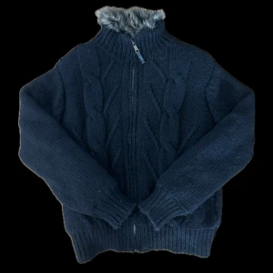 Fodrad cardigan - Säljer en svart fodrad cardigan från Zara med dragkedja och fuskpälsdetaljer på kragen. Den har långa ärmar och ribbade muddar. Perfekt för kyliga dagar. Tröjan är tjock och skön. Storleken är XL men passar mig som bär  L-M.