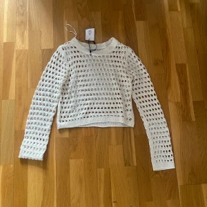 Vit stickad croppad tröja från Stradivarius - Säljer en vit stickad croppad tröja från Stradivarius. Tröjan har ett öppet, hålmönstrat stickat material och långa ärmar. Har aldrig använt och har kvar prislappen💘 