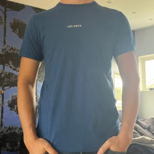Blå t-shirt från Les Deux - Säljer en go blå tisha från Les Deux. Knappt använd så grymt bra skick🤩 storlek M och normal i passformen. Skriv vid frågor eller funderingar👍🏼