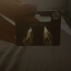Guldiga droppformade örhängen från Montini - Säljer ett par snygga guldiga örhängen i droppform från Montini. Perfekta för att ge din look lite extra glans. Enkla att matcha med olika outfits och passar dig som gillar stilrena accessoarer. De är helt helt nya har aldrig tagit på mig min syster köpte den igår och hon kunde inte lämna tillbaks den.