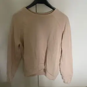 En enkel och stilren beige sweatshirt med rund halsringning och långa ärmar. Perfekt för en avslappnad look och lätt att matcha med andra plagg.