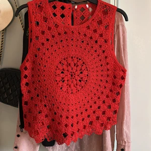Röd virkad croppad linnetopp🍓🍓 - Säljer en röd virkad croppad linnetopp med blommigt mönster. Toppen är ärmlös och har rund halsringning. Perfekt för sommaren och ger en bohemisk känsla till outfiten.