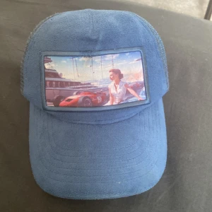 Riktigt fet Blå keps från Revenite med motiv - Riktigt fet blå keps med nät där bak och ett litet håll på sidan men den är också limited edition. Väldigt värt att köpa och är i hyfsat bra skick. Skriv gärna för mer frågor eller bilder och pris kan diskuteras!🤩(använd några gånger men fastnade så de blev hål)