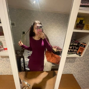 Mörklila ribbad klänning från FB Sister - Säljer en mörklila ribbad klänning från FB Sister i storlek M. Klänningen är tight och har lång ärm, perfekt för dig som gillar en enkel men snygg look. Den är kort i modellen och har en rund halsringning.