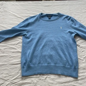 Ljusblå tröja från Polo Ralph Lauren - Säljer en ljusblå långärmad tröja från Polo Ralph Lauren i mjuk pima cotton. Klassisk rund halsringning och diskret broderad logga på bröstet. Perfekt för en stilren och avslappnad look. Padmssar dig ifrån 158-167