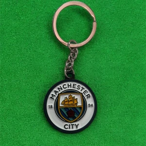 Manchester City nyckelring - Säljer en rund nyckelring med Manchester Citys klubbmärke. Nyckelringen har detaljer i blått, vitt, gult och svart samt klubbens logga i mitten. Perfekt för fotbollsfans som vill visa sitt stöd.