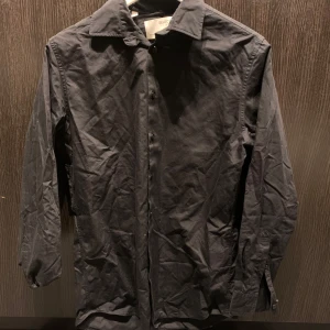 Svart skjorta från Selected Homme - Klassisk svart skjorta från Selected Homme i slim fit-modell. Skjortan har långa ärmar, knappar framtill och en stilren design som passar till många tillfällen. Tillverkad i mjukt bomullstyg för en bekväm känsla.
