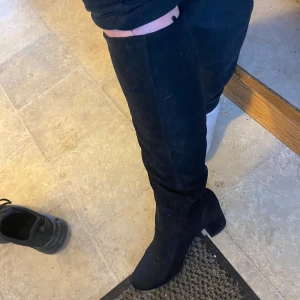 Svarta höga stövlar med klack - Säljer ett par svarta höga stövlar med klack. Skorna går över knäet och har en rund tå. Perfekta för att lyfta vilken outfit som helst och ger en snygg siluett.