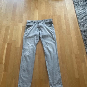 Ljusgråa slim fit jeans från Replay Anbass - Säljer ett par ljusgråa jeans från Replay Anbass med slim fit-passform. Klassisk femficksdesign och diskreta sömmar på bakfickorna. Perfekta för dig som gillar en smalare siluett och stilren look. Storlek 30 32.