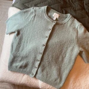 Kortärmad stickat tröja - Superfin ljusgrön stickad kofta från H&M med korta ärmar och glansiga pärlknappar framtill. Tröjan är näst intill oanvänd. Skriv för fler bilder eller vid frågor😊