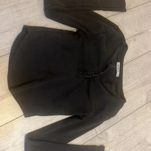 Svart ribbad långärmad topp från STAY - Svart ribbad långärmad topp från STAY i storlek XS. Toppen har knappar framtill och en lätt v-ringning. Perfekt för lager-på-lager och enkel att matcha med olika outfits. Den är köpy från Carlings(org pris 400kr). /Knappt använd/står inte för postens slarv