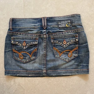 Assnygg jeanskjol - Jättecool lågmidjad jeanskjol från cocobong med massa detaljer! köpt på seacondhand men ser helt oanvänd ut! Midjemått: 40-41cm. kjolens längd från överkant till underkant: 32 cm. Bara att skriva vid frågor eller intresse!💞