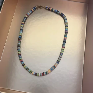 Färgglatt pärlhalsband - Säljer ett halsband med små, runda pärlor i olika färger. Halsbandet har ett klassiskt lås och passar perfekt för dig som gillar färgglada accessoarer.