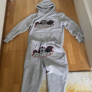 Grå Trapstar Shooters tracksuit - Säljer en grå tracksuit från Trapstar London med stor broderad logga och texten 'Shooter' på bröstet. 🤩Helt ny och oanvänd, storlek M😁. Ny pris runt 2499-3499 kr. Pris kan diskuteras. Kan även bytas.