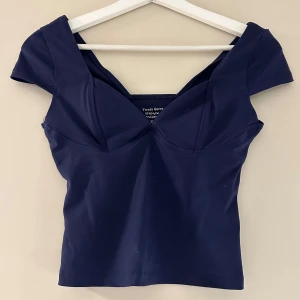Mörkblå croppad topp med v-ringning - Säljer en mörkblå croppad topp med snygg v-ringning och korta ärmar🤍 Aldrig använd ❤️ köpt för 490kr