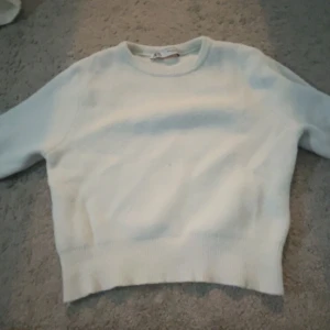 Vit stickad tröja från Zara - Säljer en stilren vit stickad tröja från Zara. Tröjan har en klassisk rund halsringning och ribbade detaljer vid ärmslut och nederkant. Perfekt för en enkel o snygg stil❣️