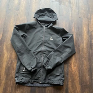 GORE-TEX  vindjacka från Haglöfs - Säljer en svart vindjacka från Haglöfs med huva och dragkedja. Jackan har långa ärmar och två fickor med dragkedja framtill. Perfekt för blåsiga dagar. Priet är ej hugget i sten.