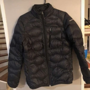 Mörkblå dunjacka från Peak Performance - Säljer en svart dunjacka från Peak Performance. Jackan har en dragkedja framtill och en bröstficka med dragkedja. 