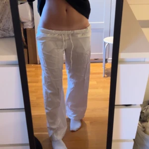 Vita lågmidjade linnebyxor - Säljer ett par vita linnebyxor med snörning i midjan.(nervikta) men brukar ha dem såhär så dem är low waist. Byxorna har en avslappnad passform och är perfekta för varma dagar. De är tillverkade i ett lätt och luftigt material som ger en skön känsla.