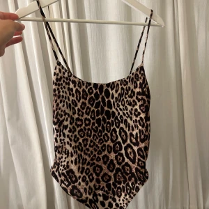 Leopardmönstrad bodysuit - Trendig leopardmönstrad bodysuit med smala axelband. Säljer då den inte kommer till någon användning. Använd 1 gång.