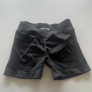 Svarta träningsshorts från DFYNE - Snygga svarta träningsshorts från DFYNE med hög midja och en tight passform. Perfekta för gymmet eller löprundan. Tillverkade i ett stretchigt syntetmaterial för optimal rörelsefrihet.