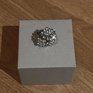 ring med stenar - Säljer en super snygg ring i silverfärg med flera gnistrande stenar. Ringen har en iögonfallande design som verkligen drar blickarna till sig. Perfekt för att lägga till lite extra glamour till din outfit.💖 ca 2x2cm 💖 storlek kan justeras på ringen💖