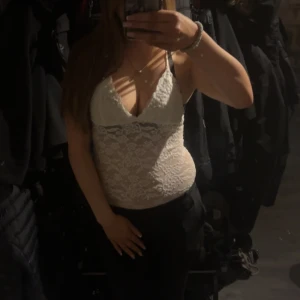 Vit spetslinne - Säljer ett elegant vit body med smala axelband och djup urringning. Perfekt för en stilren look. Passar bra till både jeans och kjol. Eller kostymbyxor 