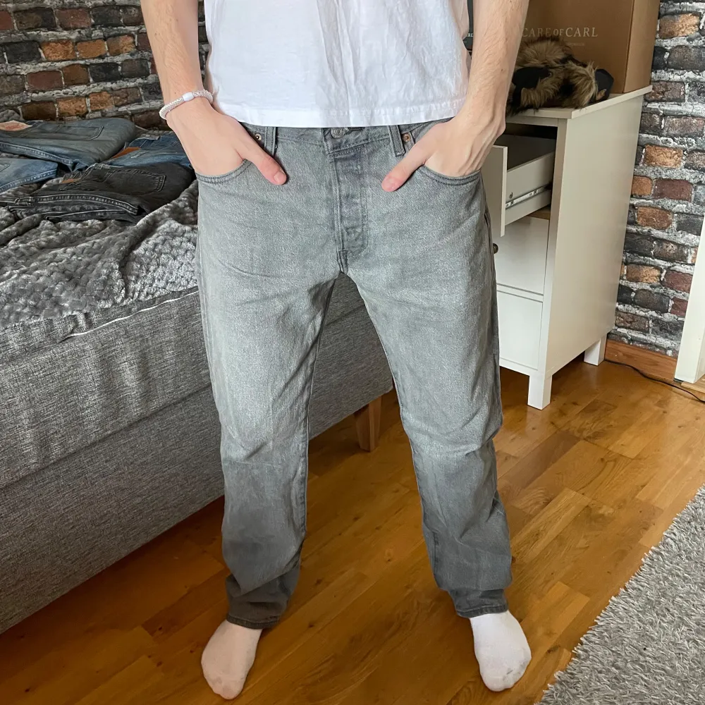 Snygga ljus grå jeans från Levi's med en klassisk femficksdesign. De har en rak passform och är perfekta för en avslappnad stil. Jeansen har en diskret tvättad look och en liten röd etikett på bakfickan. Modellen på jeansen är 501 . Farkut & Housut.