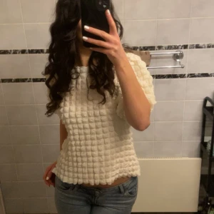 Vit ribbad topp - Säljer en vit ribbad topp med korta ärmar och ett unikt texturerat mönster. Perfekt för en stilren och modern look. Passar bra till jeans eller kjol. Bara testad. Nypris 499kr