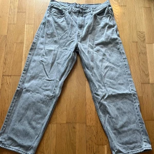 Grå Levis 578 jeans - Säljer ett par grå Levis 578 jeans med en klassisk design. De har en rak passform och är tillverkade i slitstarkt denim. Perfekta för en avslappnad stil. Jeansens baksida har två fickor och en ikonisk Levis-lapp.